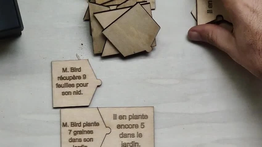 Photographie réelle de tuiles de problèmes partie-tout en bois, avec des énoncés gravés.